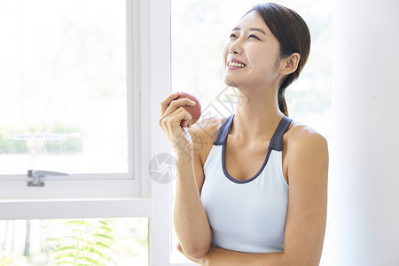 穿运动装手拿苹果的健康女性图片