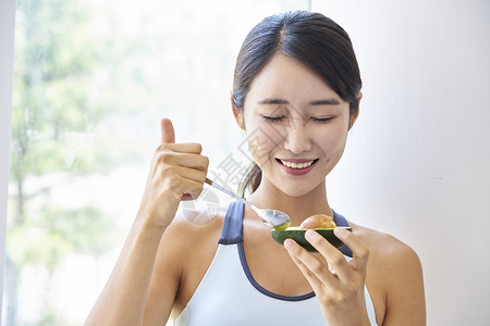 穿运动装吃牛油果的健康女性图片