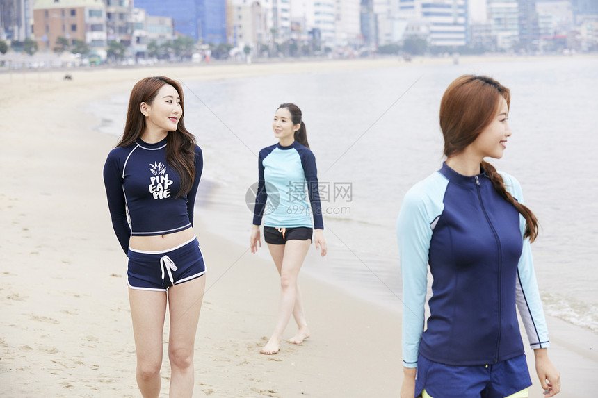 三个年轻女人在海边沙滩上散步图片