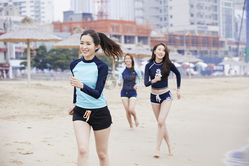 三个年轻女人在海边沙滩上散步玩耍图片