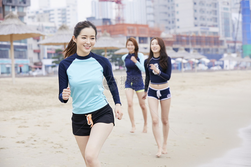 年轻女人在海边沙滩上开心运动小跑图片