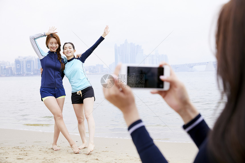 年轻女人在海边沙滩上开心玩耍拍照图片