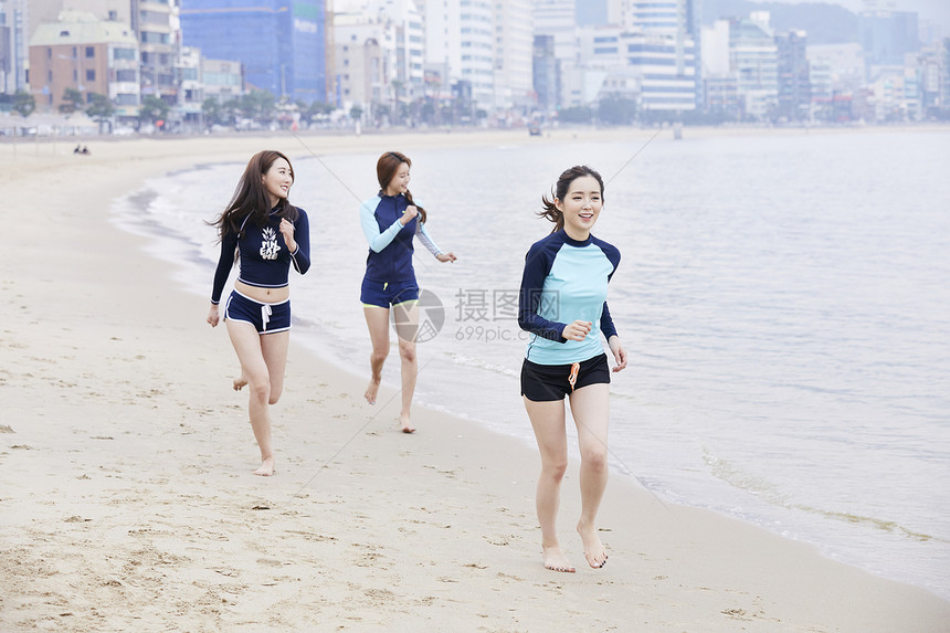 年轻女人在海边沙滩上开心运动小跑图片