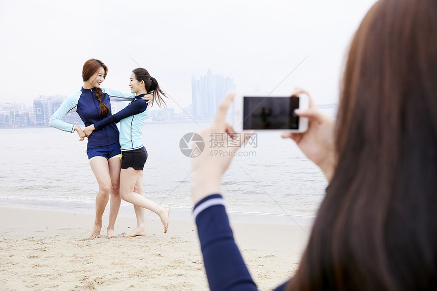 年轻女人在海边沙滩上开心玩耍拍照图片