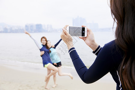年轻女人在海边沙滩上开心玩耍拍照图片