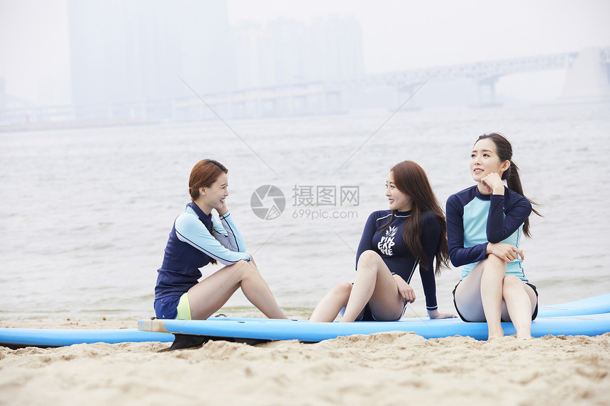 三个年轻女人坐在海边沙滩上开心聊天图片