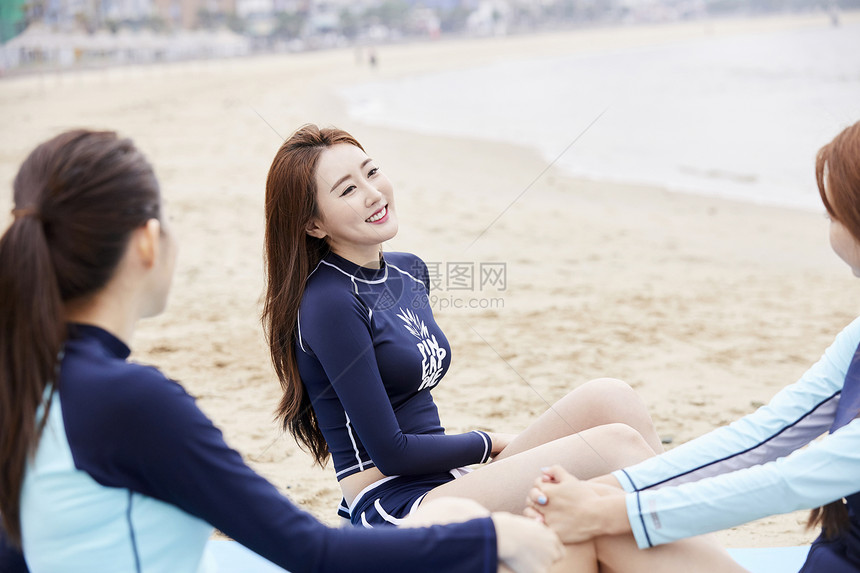 三个年轻女人坐在海边沙滩上开心聊天图片