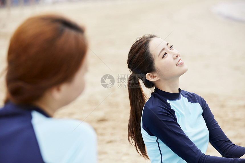 年轻女人坐在海边沙滩上开心聊天图片