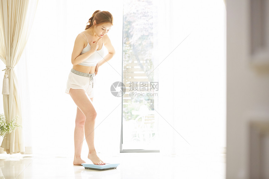 体重管理站上体重秤的女性图片