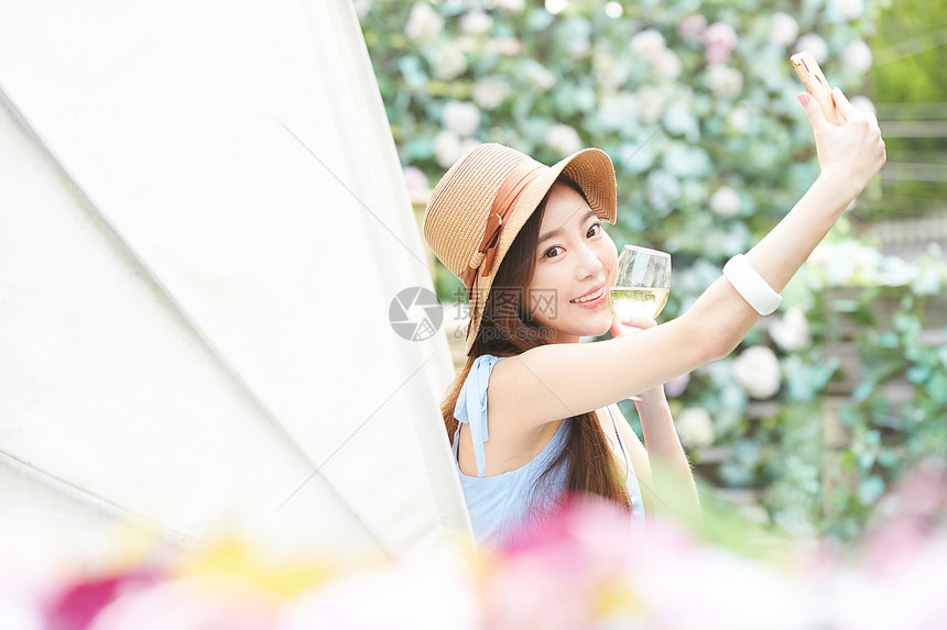 年轻女子拿着酒杯开心自拍图片