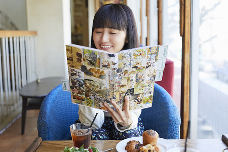 咖啡馆看漫画微笑的年轻女子图片