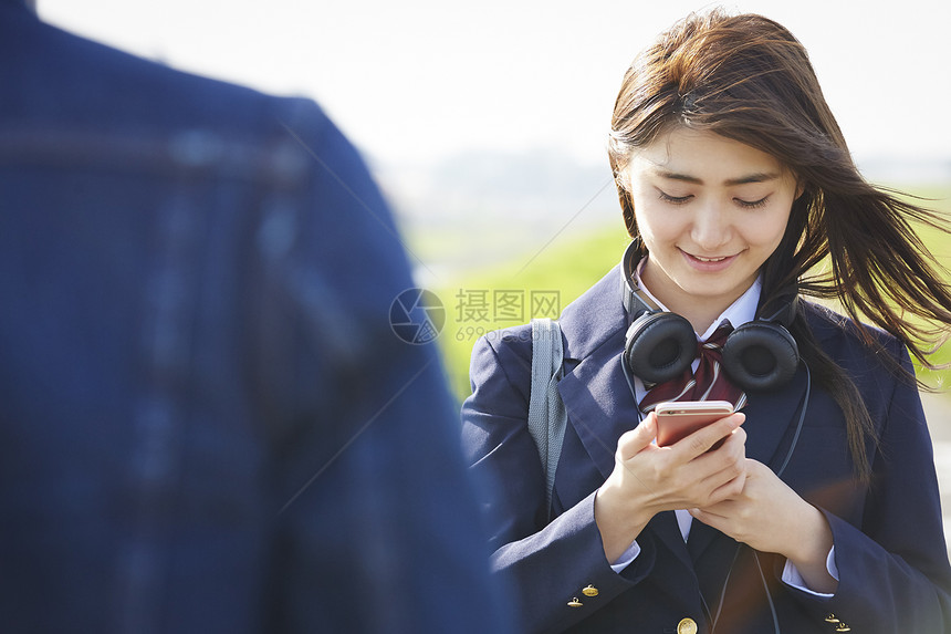 户外的可爱日系女高中生玩手机图片