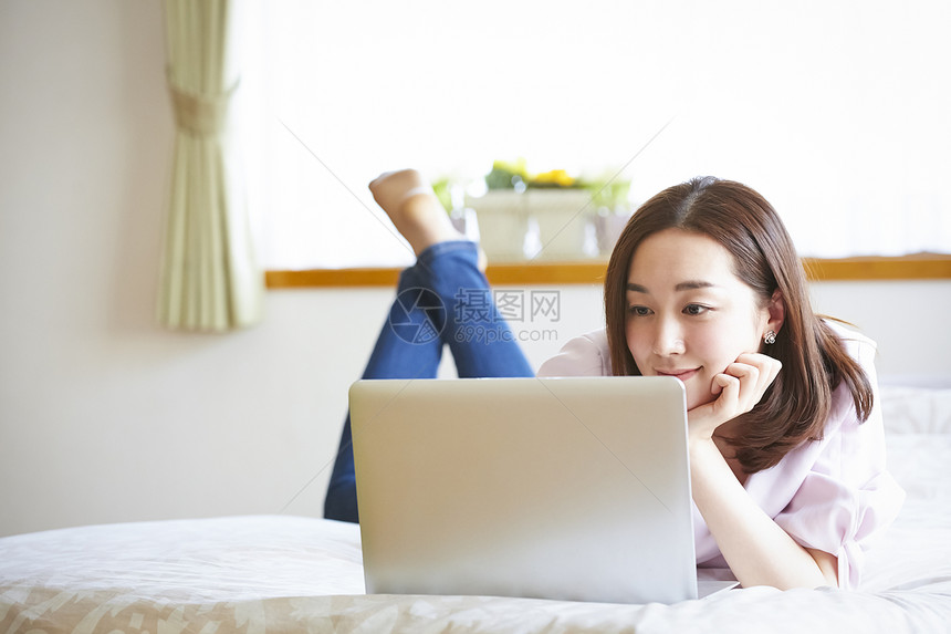 年轻女人躺在床上看电脑图片
