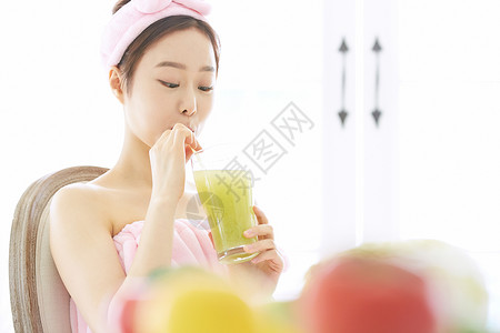 低头喝果蔬汁的年轻女子图片