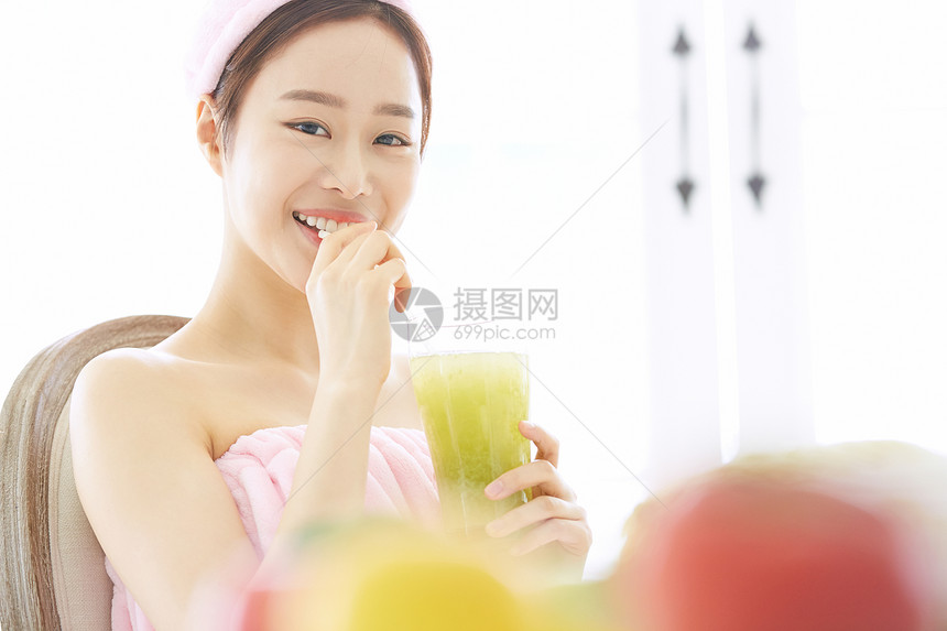 年轻女子微笑的喝蔬菜汁图片