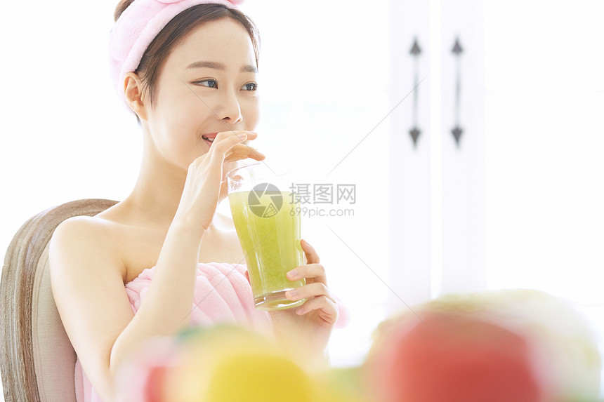 喝着蔬菜汁微笑的年轻女子图片