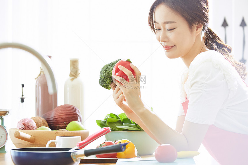 厨房里料理拿着蔬菜的年轻女子图片