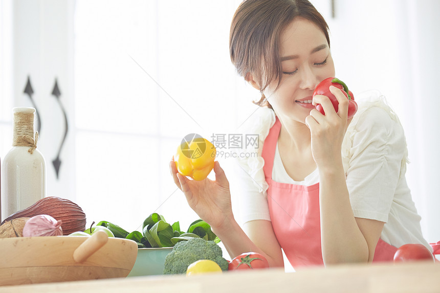 年轻女子拿着彩椒闻图片