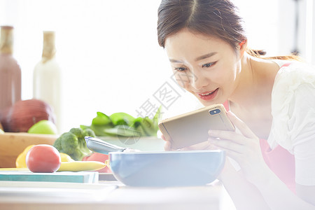 拿着手机拍食物照片的女性图片