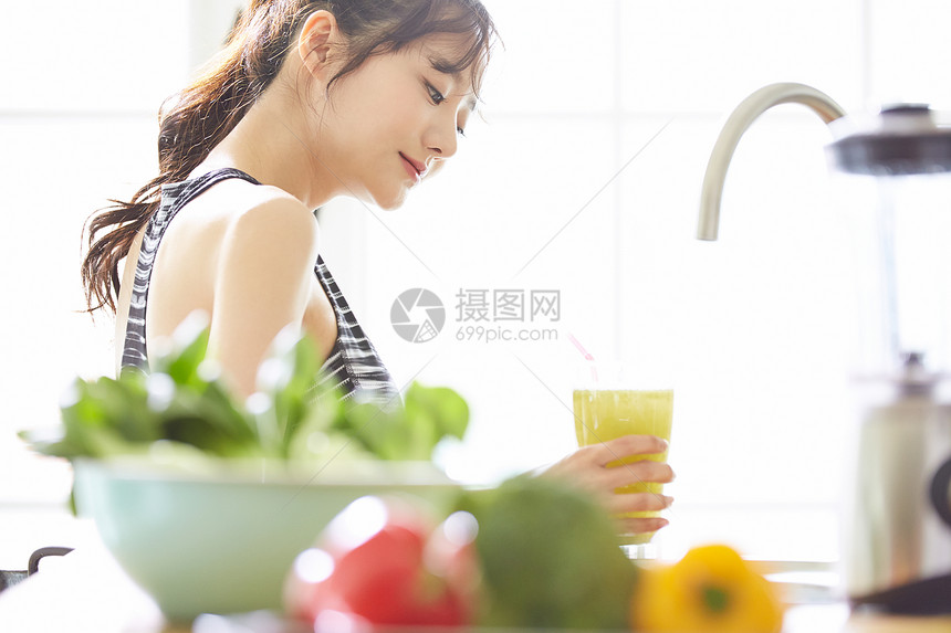 年轻女子拿着蔬菜汁图片