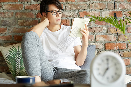 戴眼镜的男人坐在沙发上看书图片