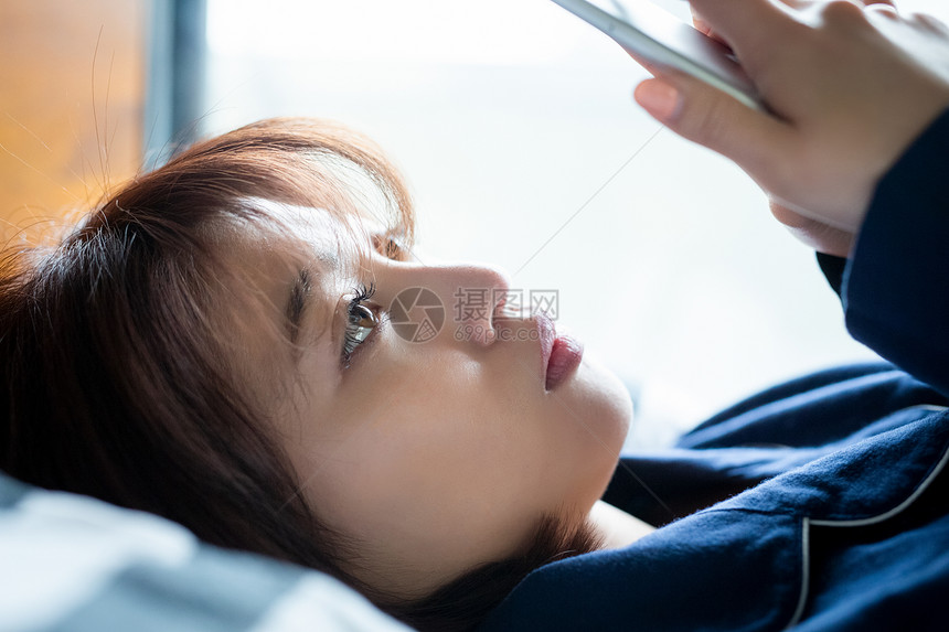 女人在床上看手机特写镜头图片