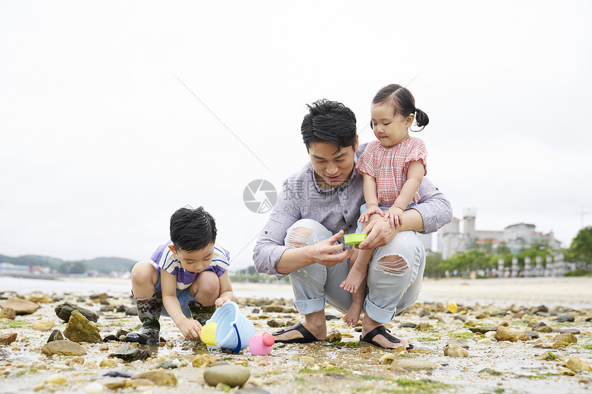 在海边捡石子的一家人图片