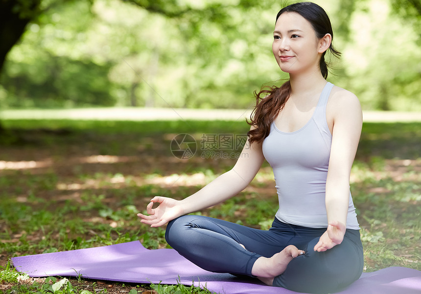 瑜伽垫上盘腿坐的青年女性图片