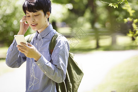 戴上耳机低头看着手机的男子图片