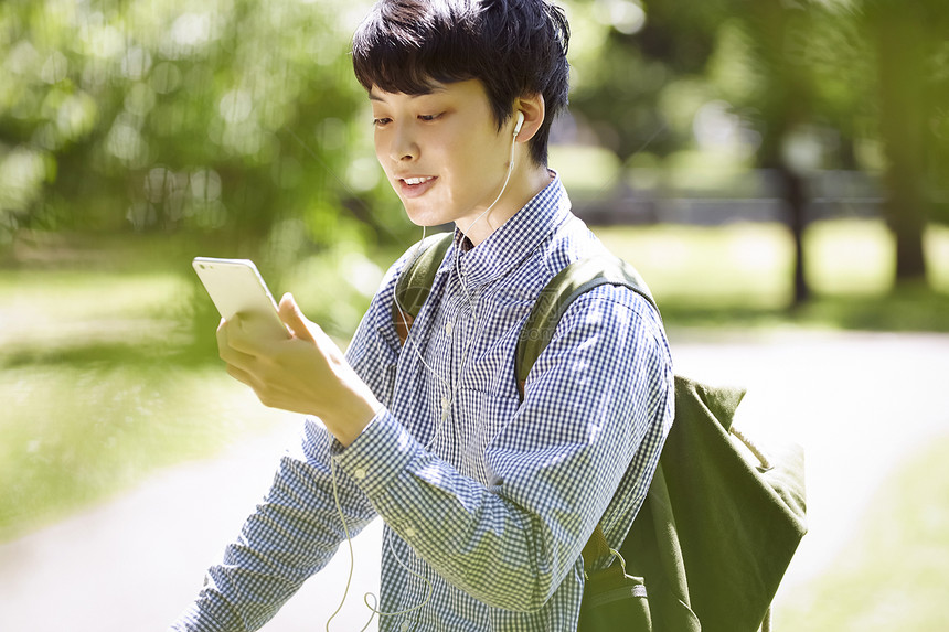 看着手机微笑的男青年图片