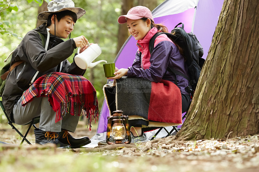 野外露营倒茶开心的年轻情侣图片