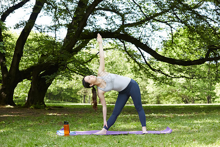 女青年在公园草地上做瑜伽拉伸图片