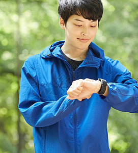 户外公园跑步看手表的年轻男子图片