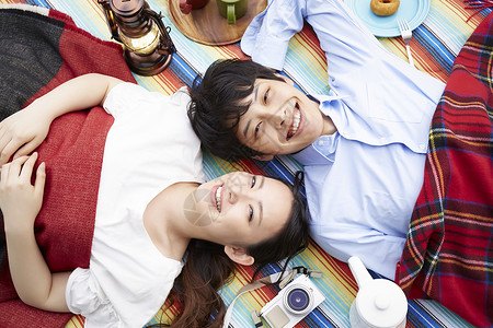 躺在野餐垫上微笑的年轻情侣图片