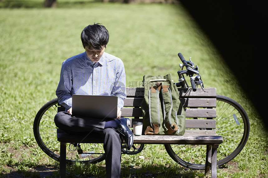 坐在长凳上使用笔记本电脑的男人图片