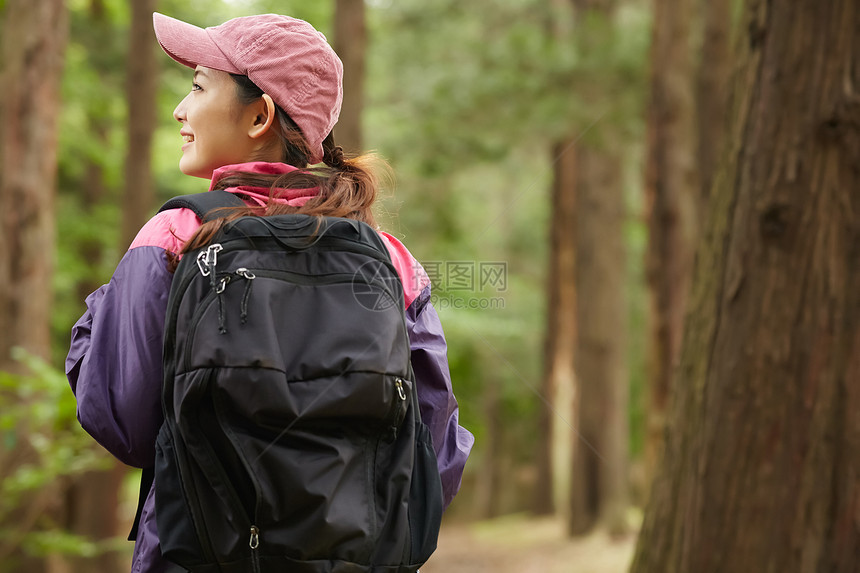 森林里远足背着背包的女青年背影图片