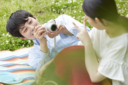 户外野餐拿着相机给妻子拍照的男性图片