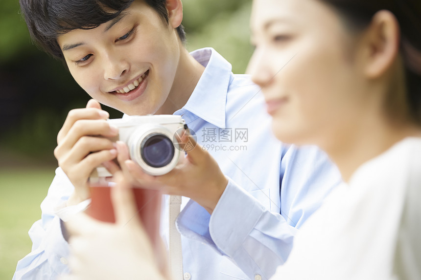 户外野餐拿着相机开心的男青年图片