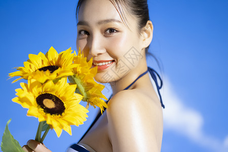 泳装女性拿着向日葵微笑图片