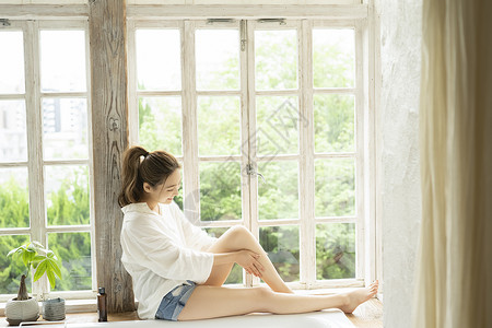 窗台上身体护理的年轻女子图片