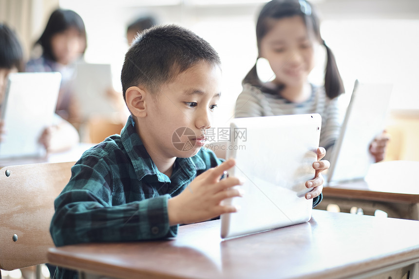 小学生在老师的指导下学习平板电脑使用知识图片