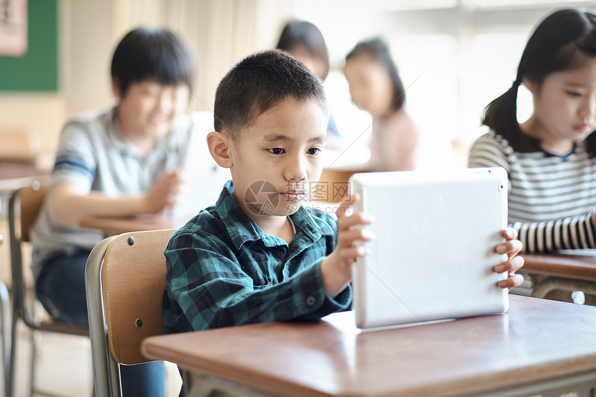 小学生在老师的指导下学习平板电脑使用知识图片