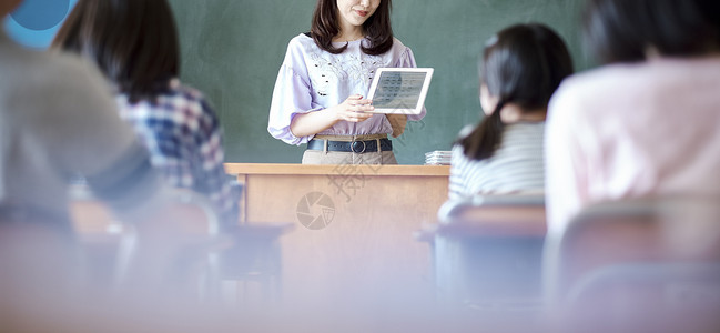 小学生在老师的指导下学习平板电脑使用知识背景图片