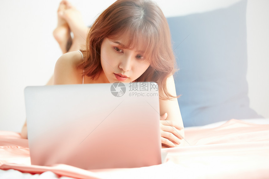 趴在床上看电脑的年轻女子图片