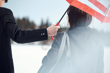 户外雪地男子给女生打伞图片