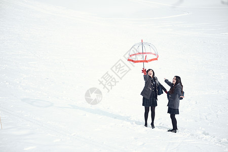 站在雪地上玩耍的女高中生图片