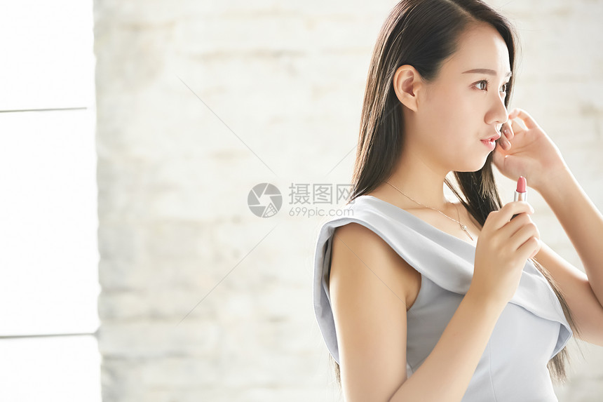 穿着晚礼服拿着口红的年轻女子图片