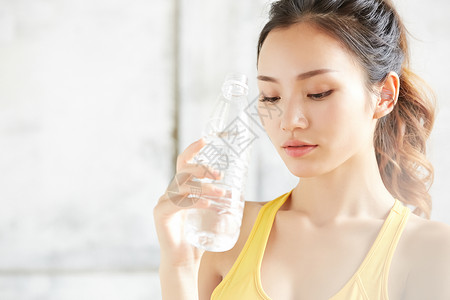 拿着水瓶喝水的运动女青年图片