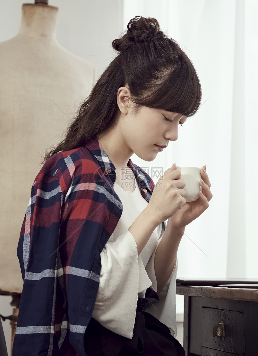 捧着咖啡放松休息的职业女性图片