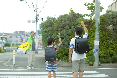 过马路的男孩老年人指导小学生去学校过马路背景